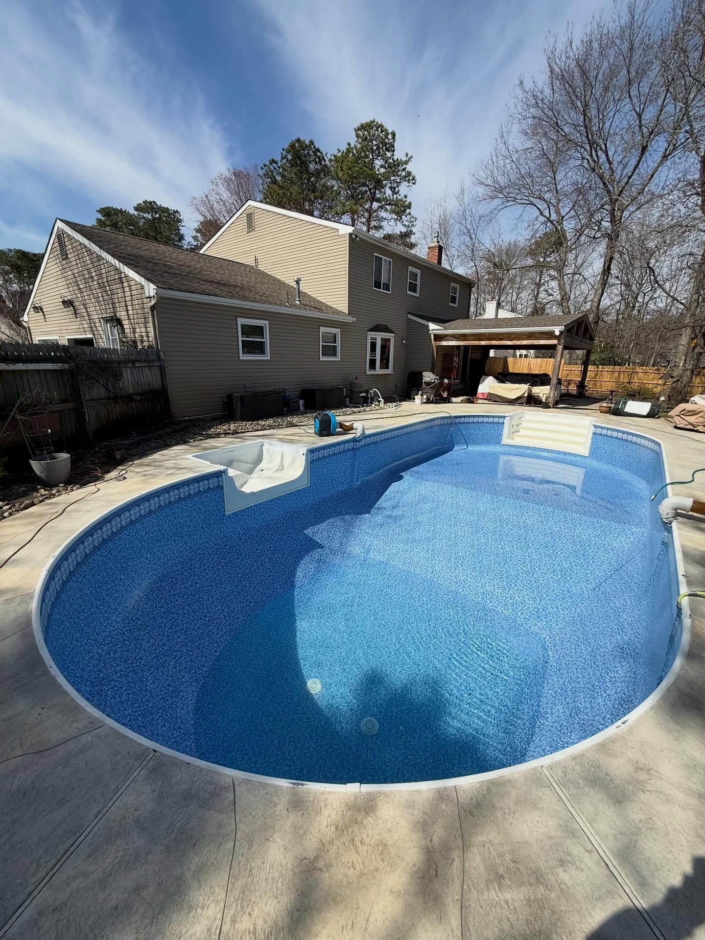 Backyard pool with blue water beside a house on a sunny day