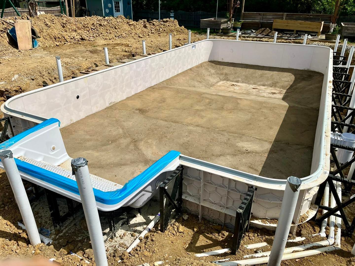A swimming pool is being built in the dirt.