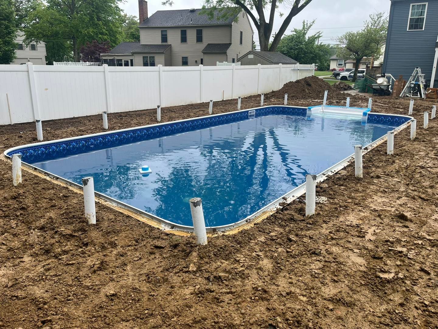A swimming pool is being built in the backyard of a house.