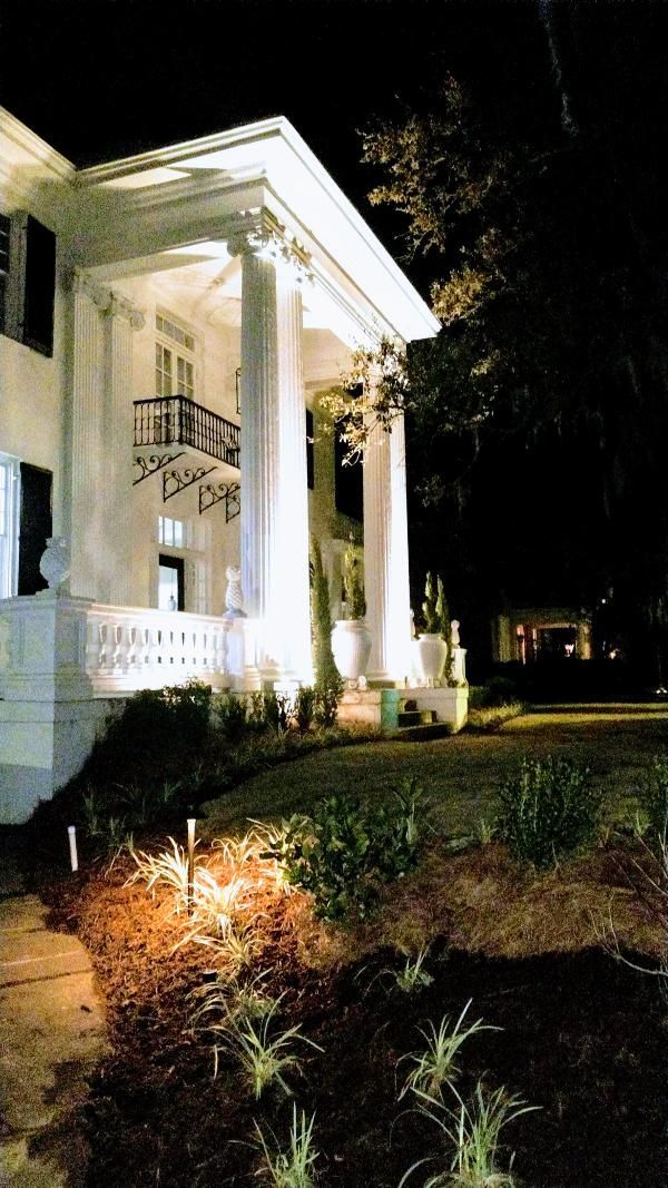 A large white house is lit up at night.