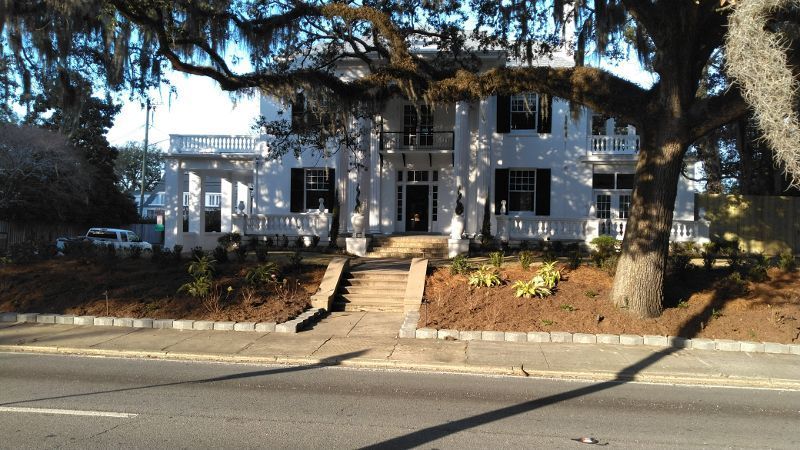 A large white house sits on the side of a road