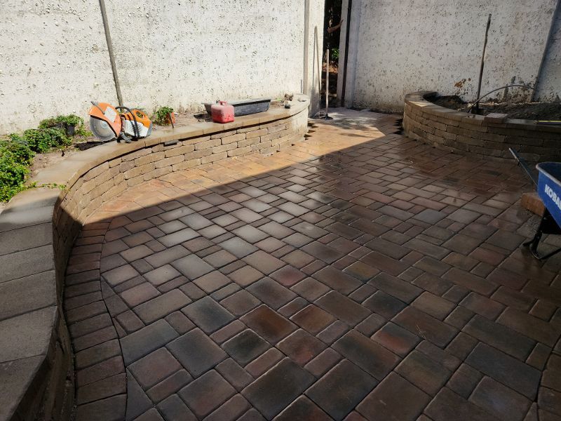 A brick patio with a stone wall and a cooler in the background.