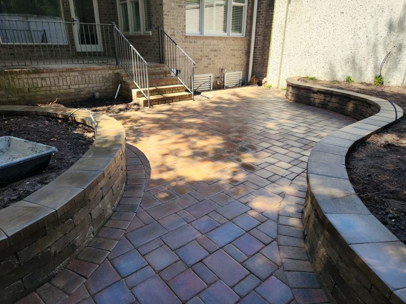A brick walkway leading to a house with stairs.