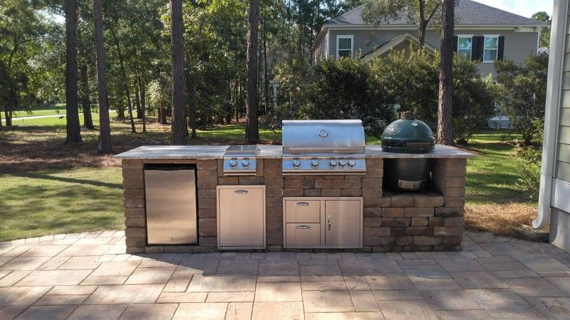 A large outdoor kitchen with a grill and a green egg.