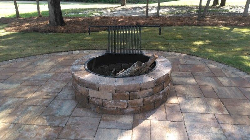 A fire pit is sitting on top of a brick patio.