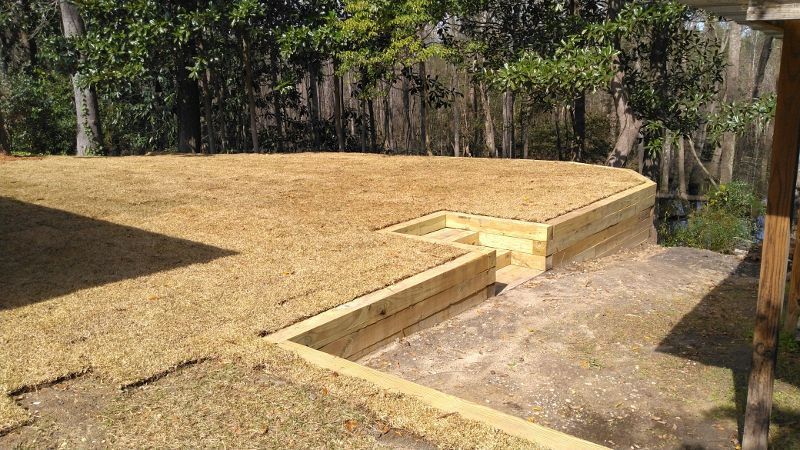 A wooden deck is being built in the backyard of a house.