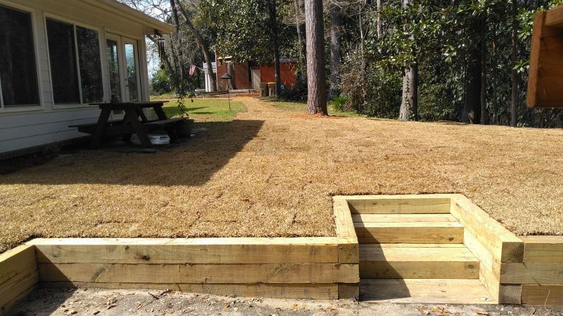 A wooden deck with stairs and a picnic table in front of a house.