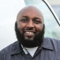 A bald man with a beard is smiling in front of a white van.