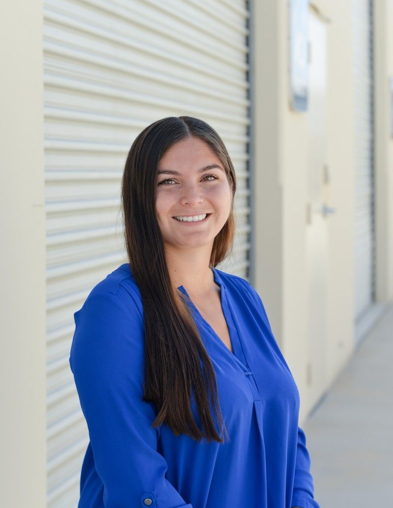 A woman in a blue shirt is standing in front of a building.
