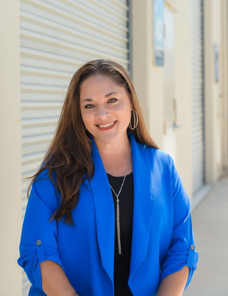 A woman in a blue jacket is smiling for the camera.