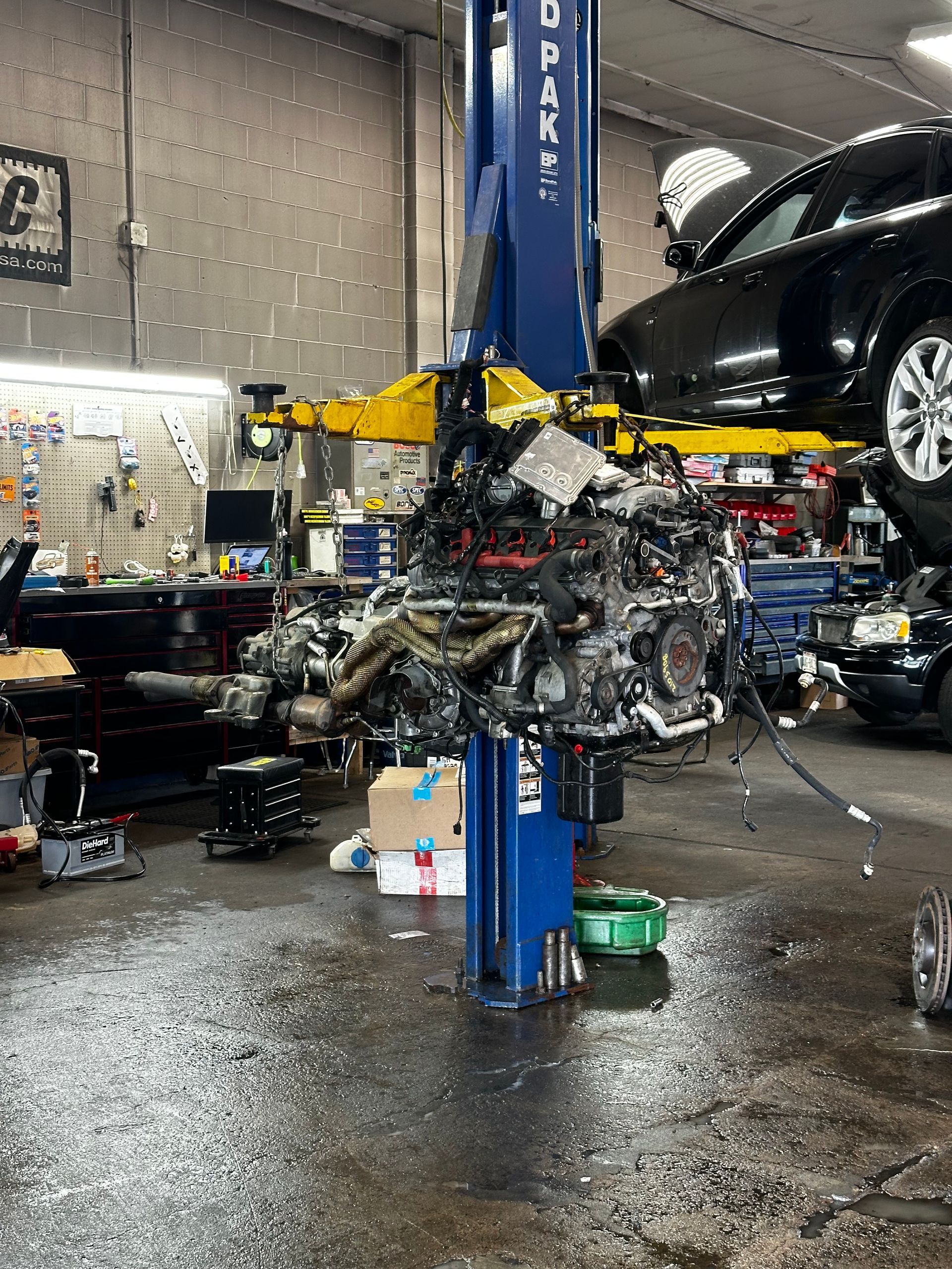 A car engine is being removed from a lift in a garage