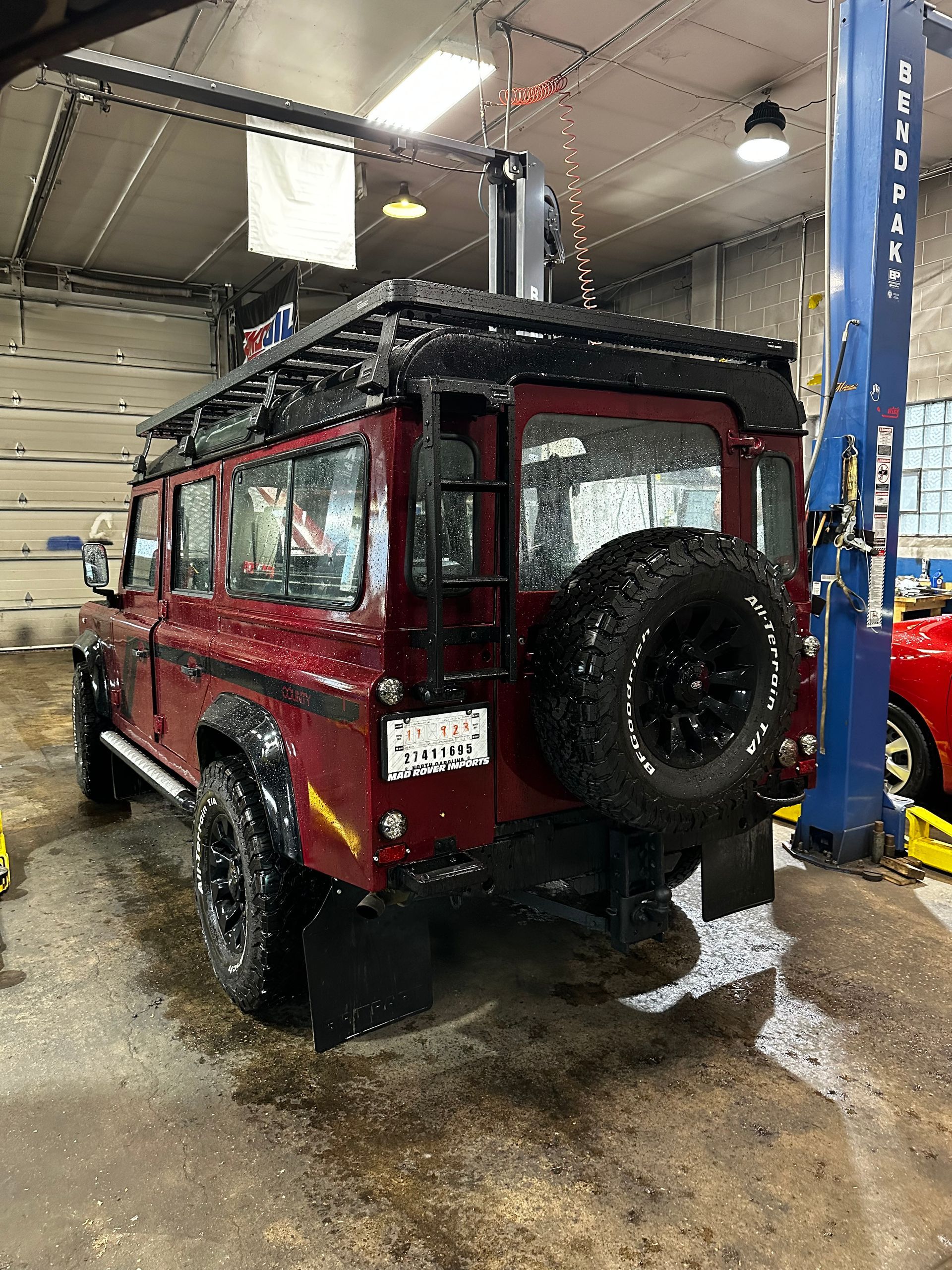 A red land rover is parked in a garage on a lift