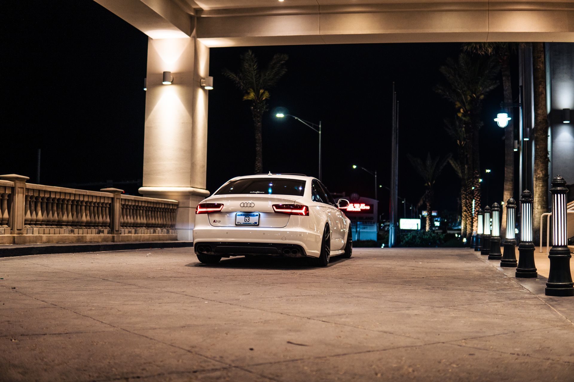 A white car is parked in a parking lot at night