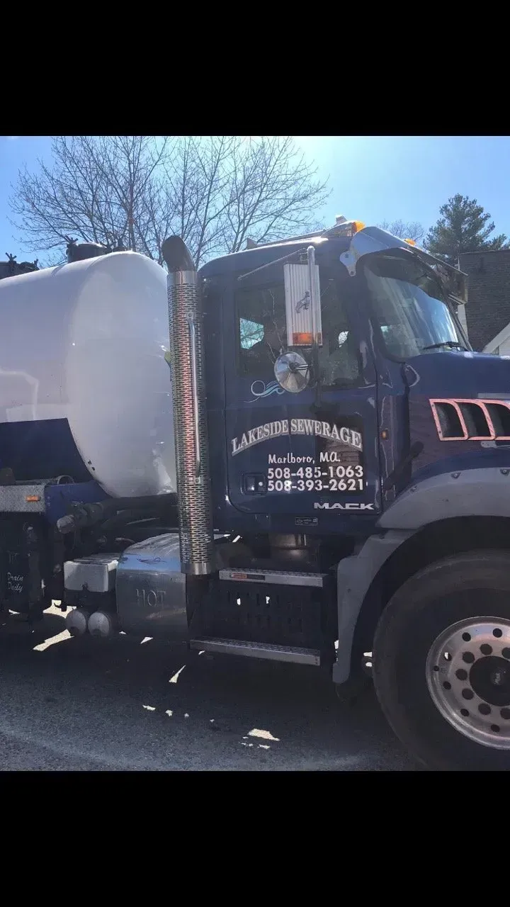 Dark blue tanker truck with silver accents and exhaust pipe parked outdoors.