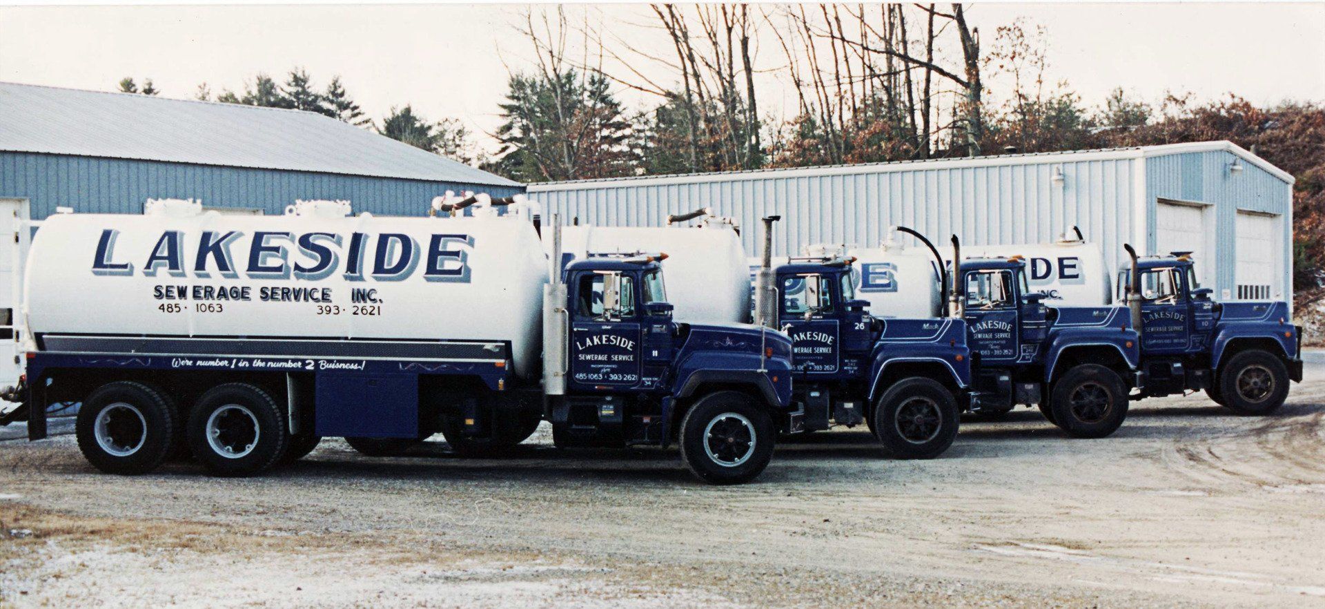 Four blue and white tanker trucks parked in a row