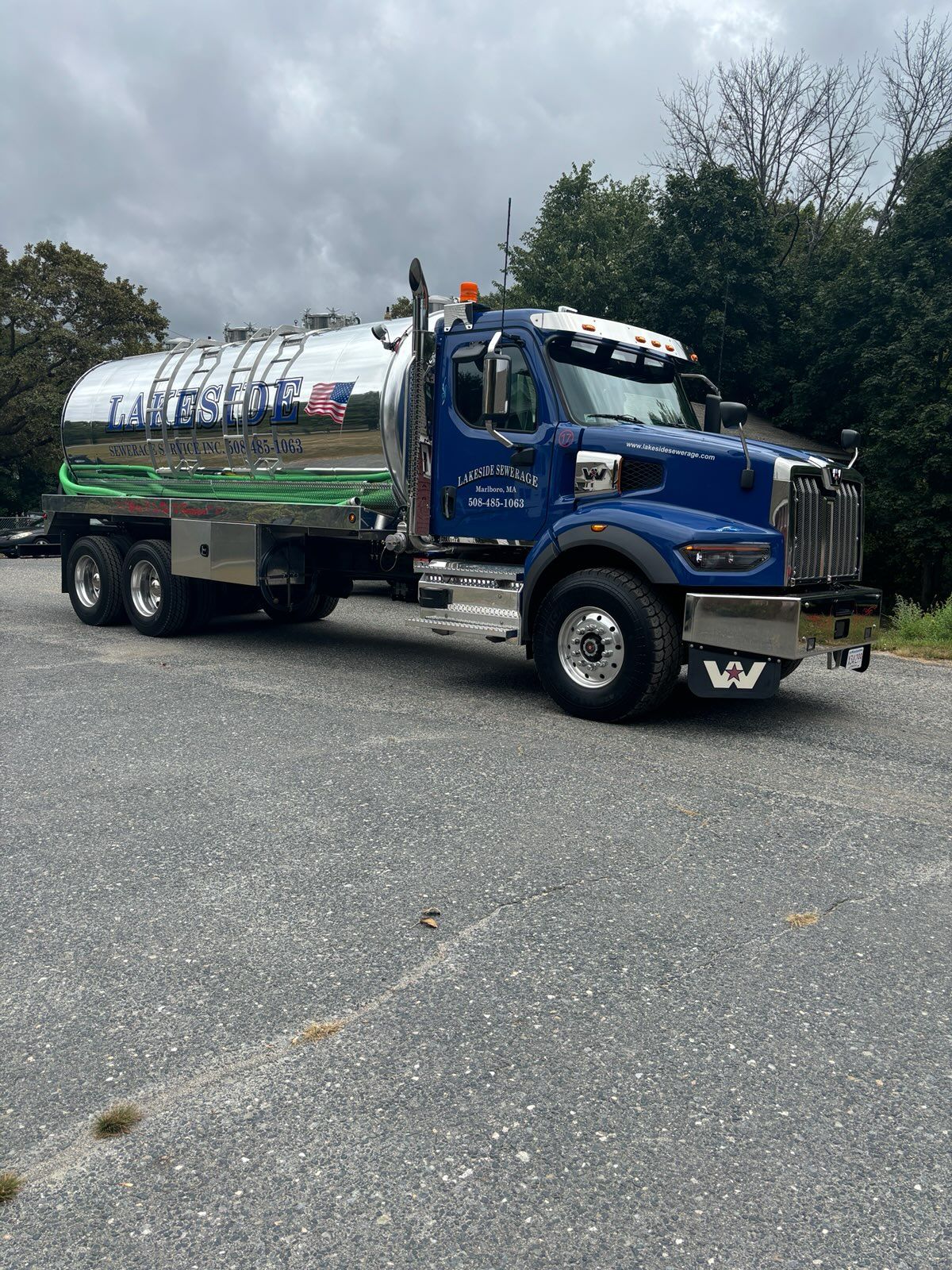 Blue tanker truck with a silver tank parked on asphalt.