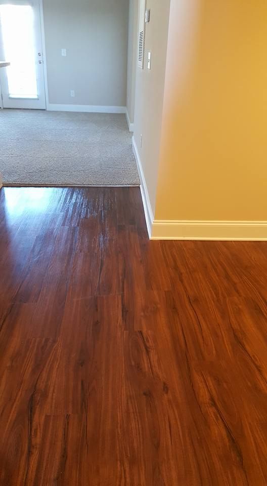 Dark wood floor transitions to beige carpet; tan walls, white trim.