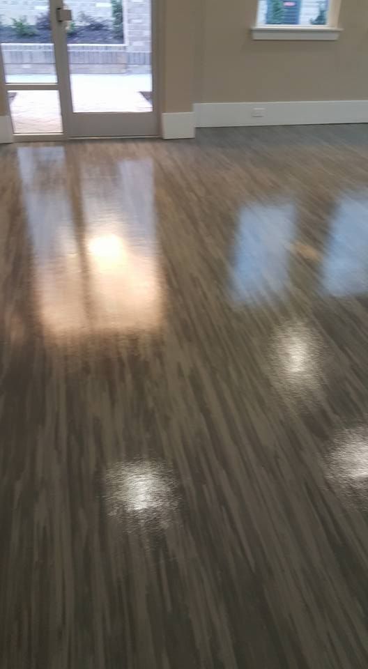 Shiny, light-brown flooring reflecting sunlight from a doorway and a window in an empty room.
