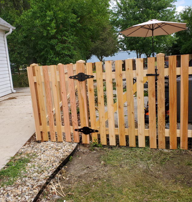 A wooden fence with a gate and an umbrella in front of it