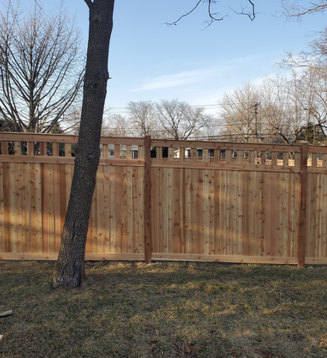 A wooden fence with a tree in front of it