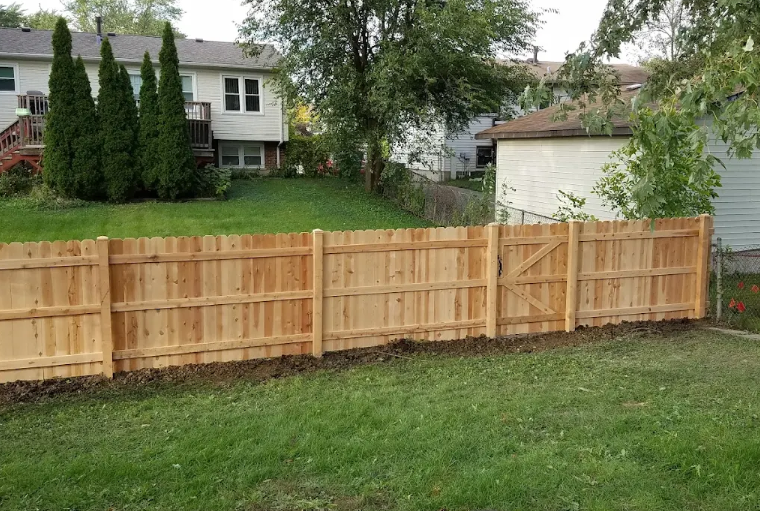 A wooden fence is in the backyard of a house.