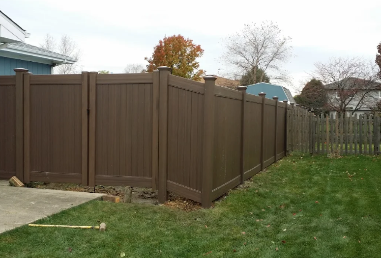 A brown fence is in the backyard of a house.