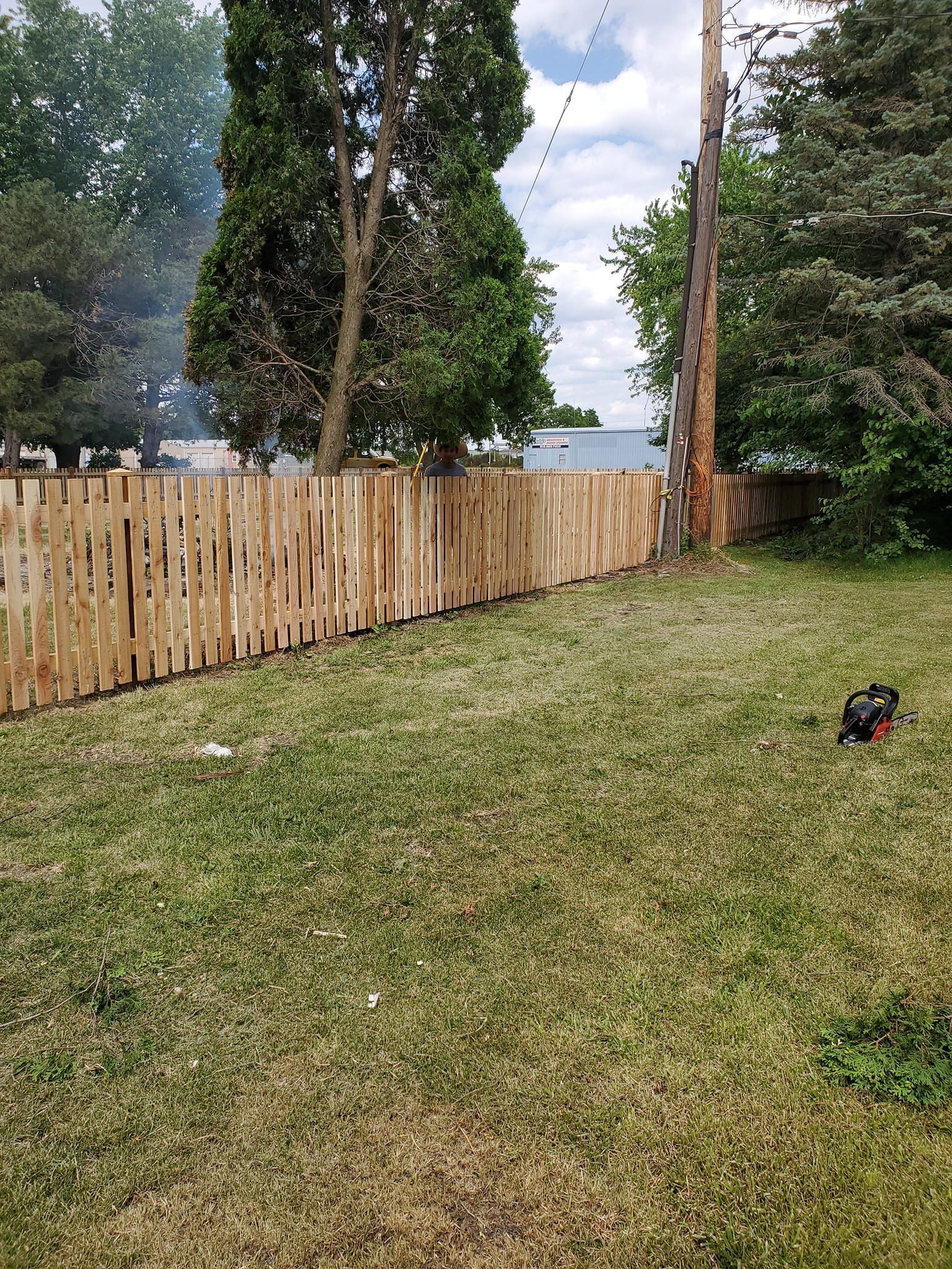 A wooden fence surrounds a lush green yard.