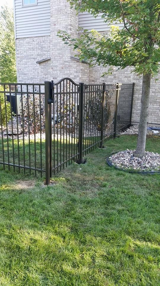 A wrought iron fence with a gate in the backyard of a house.