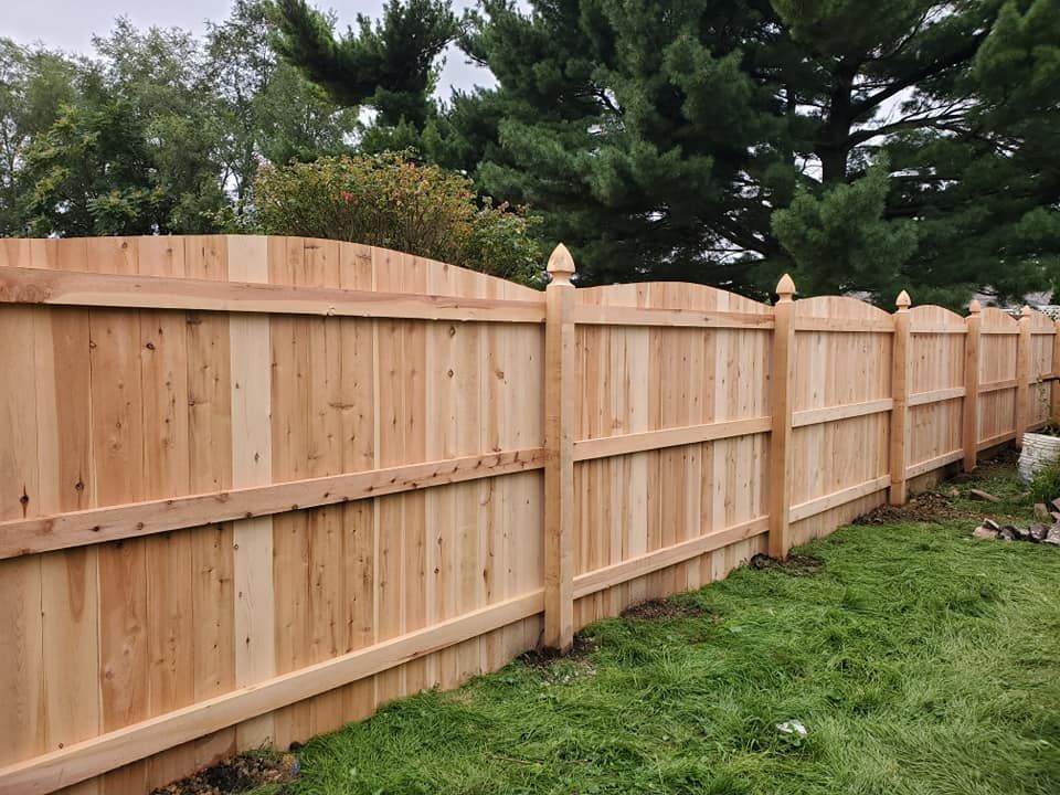 A wooden fence is sitting in the middle of a lush green field.