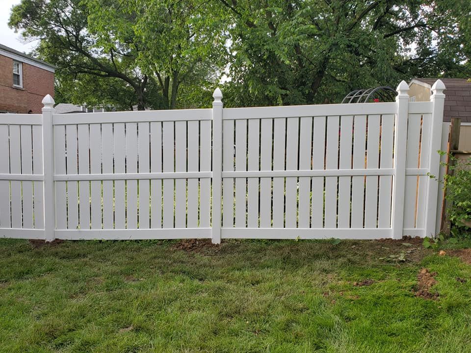 A white fence is sitting in the middle of a lush green yard.