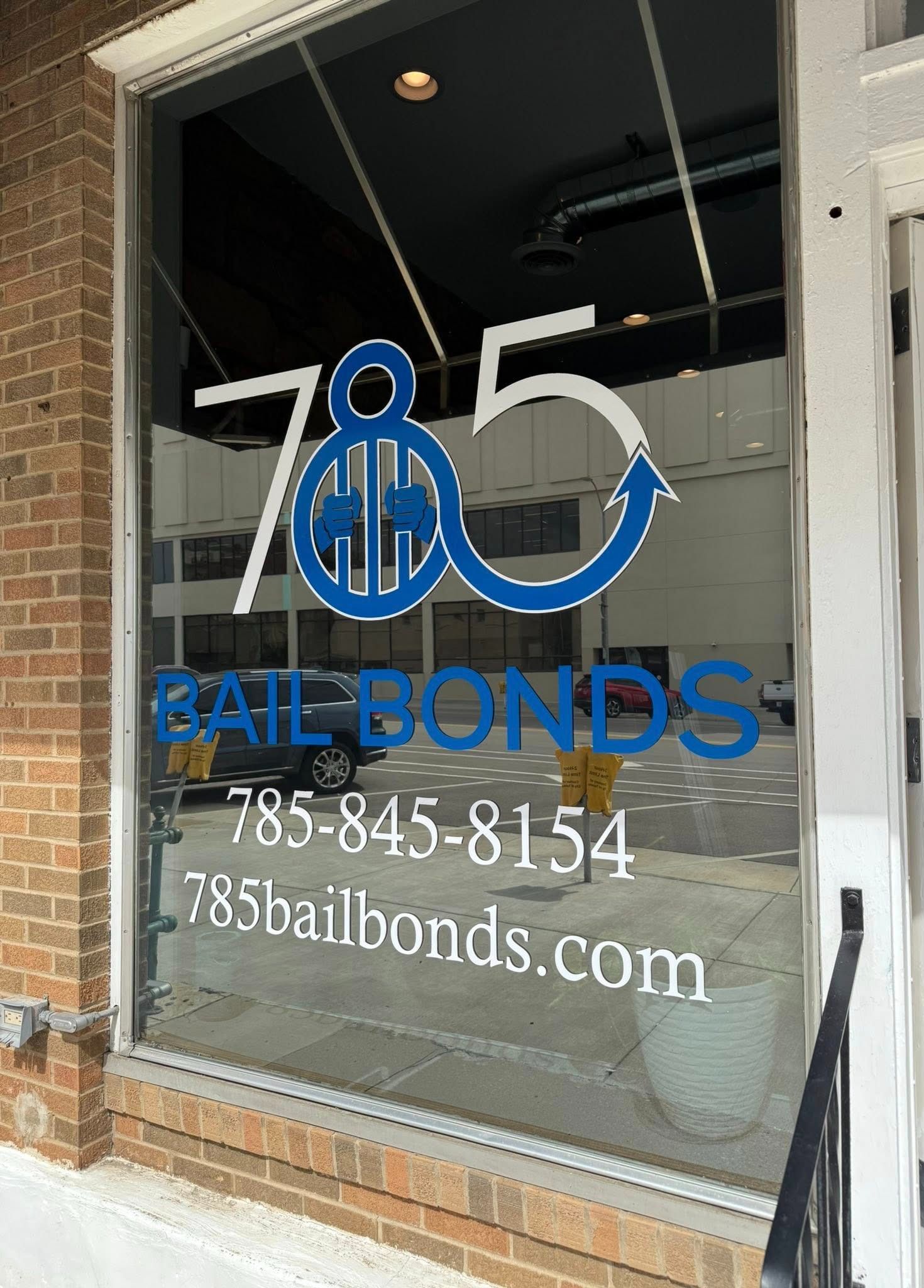 Window of a bail bonds office with blue and white lettering: '785 Bail Bonds' and contact info.