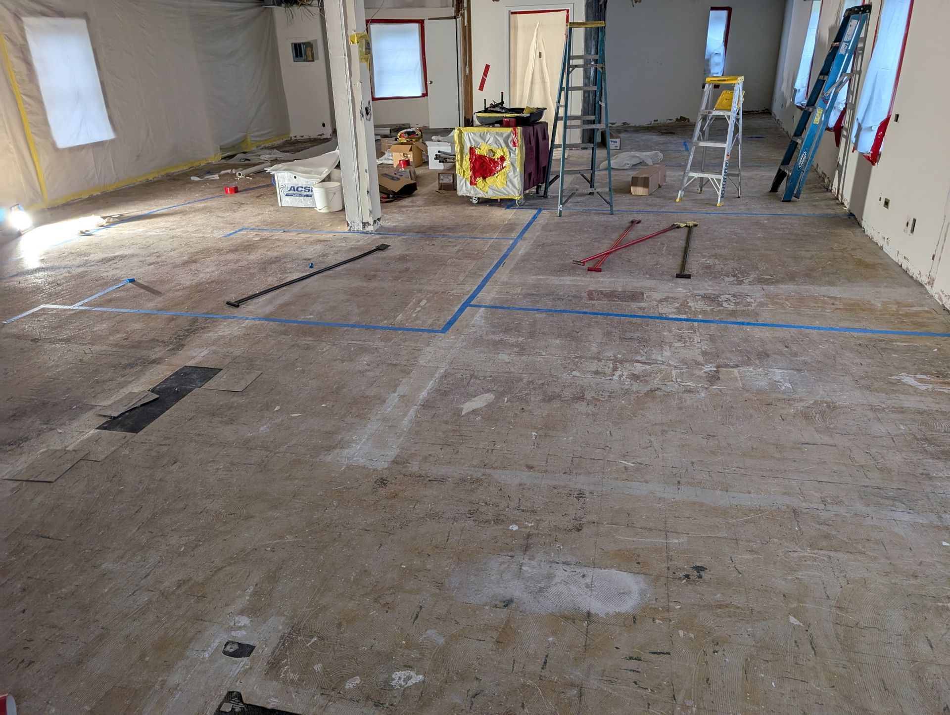 A large empty room with a ladder in the middle of it.