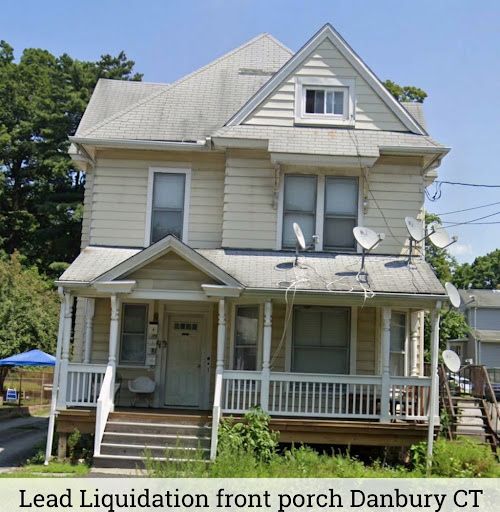 Lead Liquidation Project, Danbury, CT. Front porch of a weathered white house with satellite dishes and a fenced yard