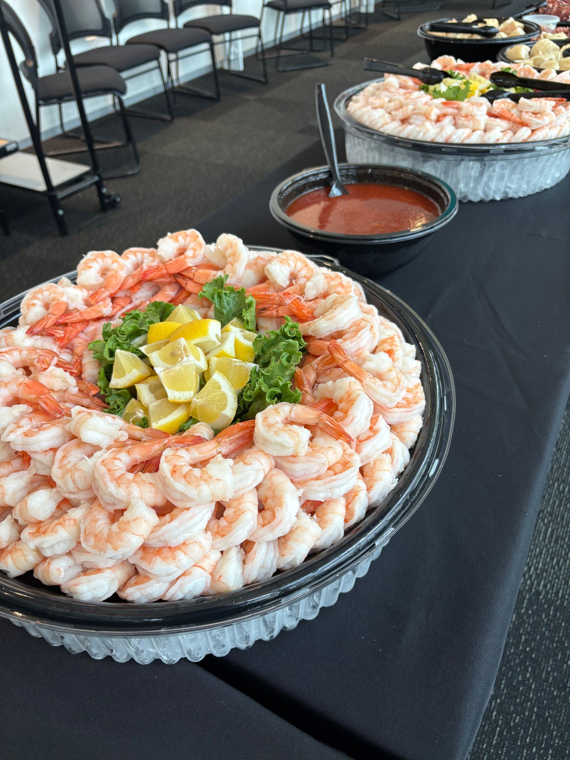 Shrimp cocktail platters with lemon, parsley, and cocktail sauce on a black table.