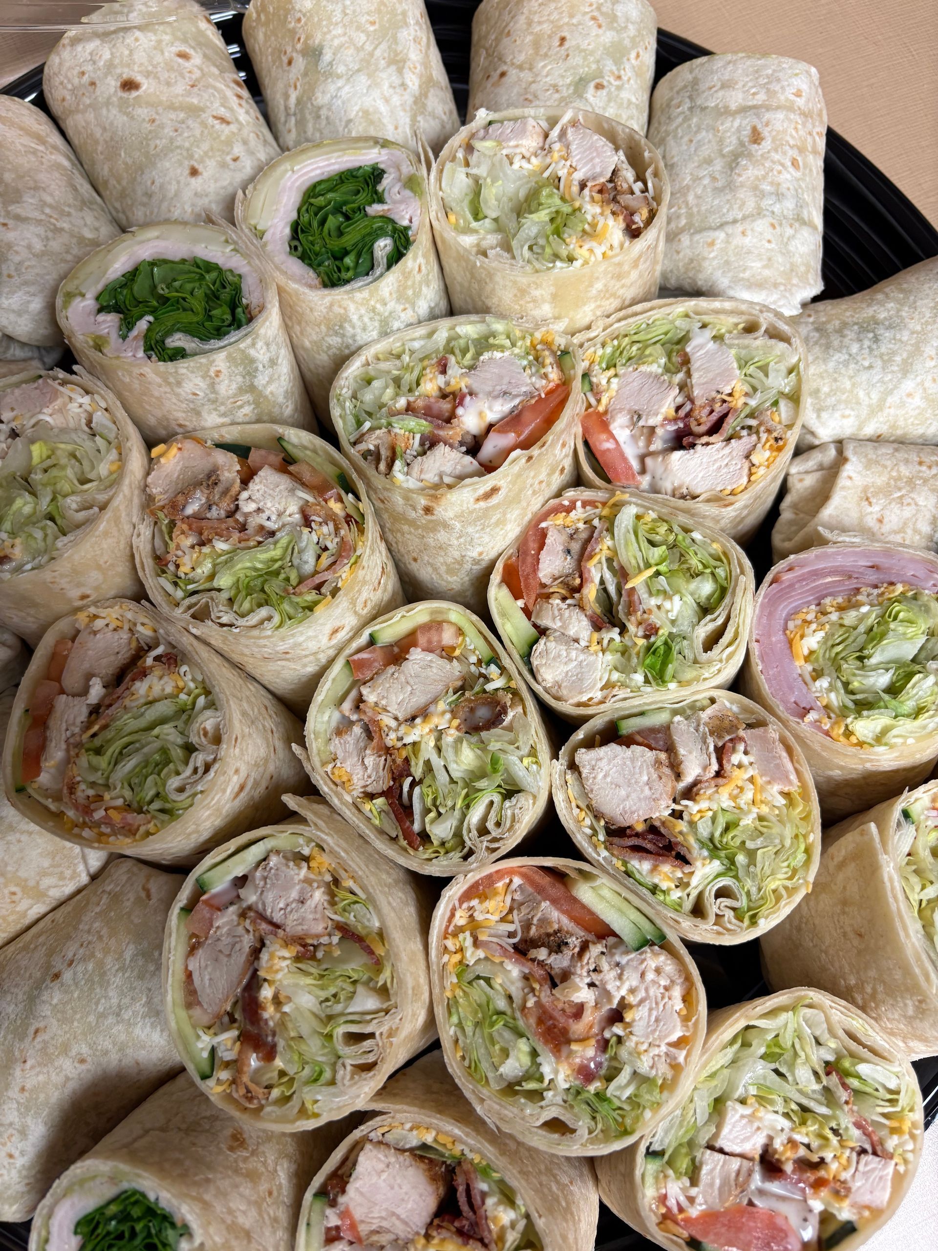 Wraps on a platter, cut into sections. Chicken and vegetable fillings are visible.