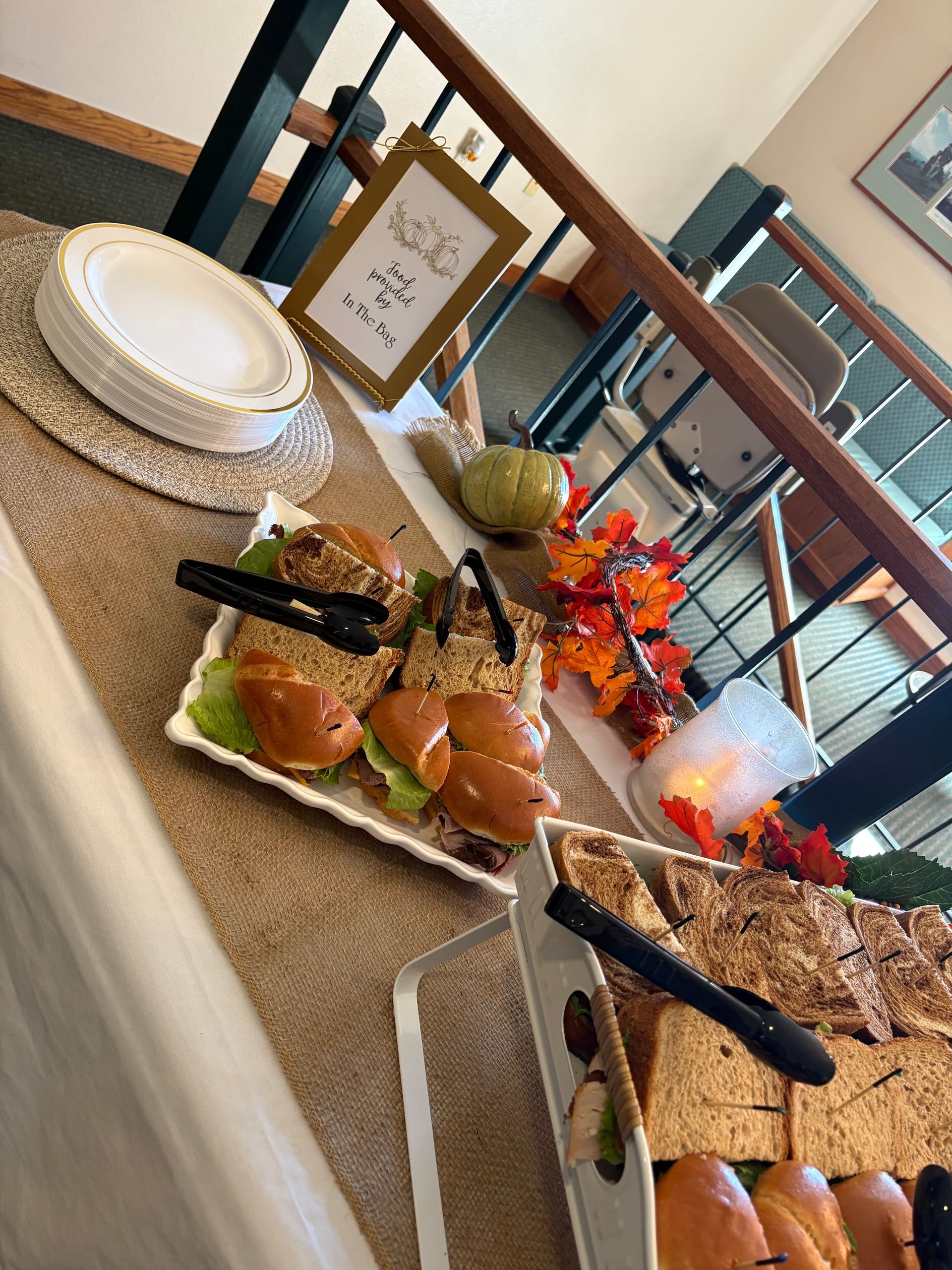 Buffet table with sandwiches, plates, and fall decorations.