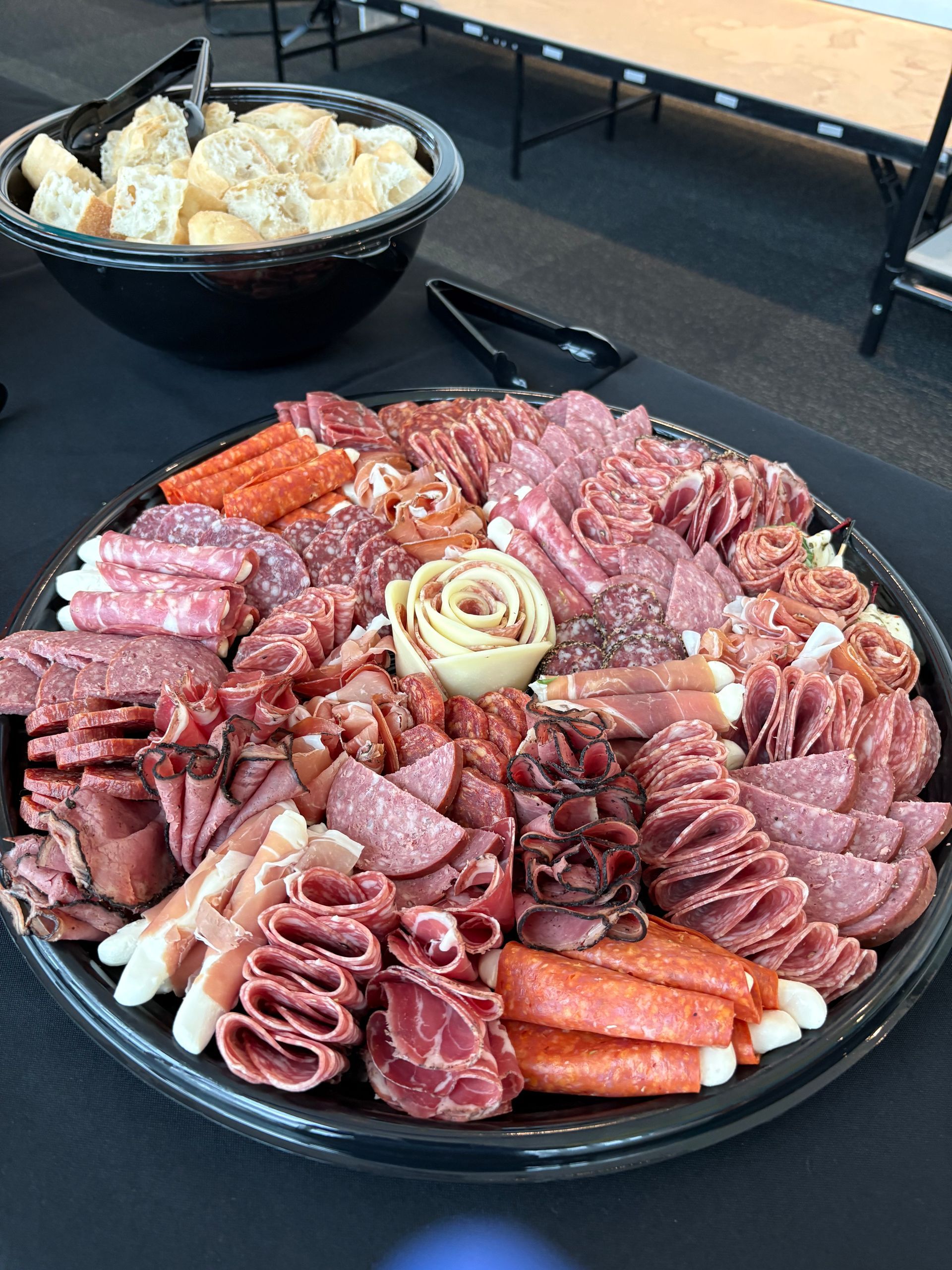 Charcuterie platter with various meats and bowl of bread.