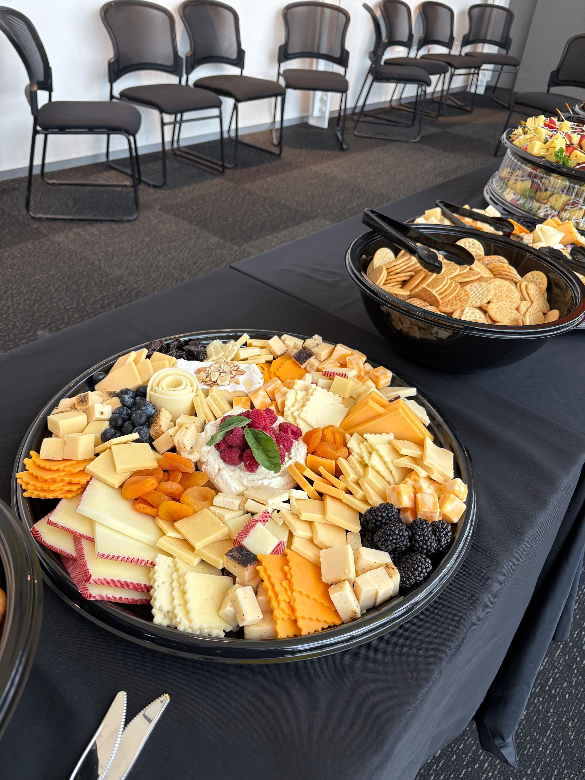 Cheese and cracker platter on a table with chairs in the background.