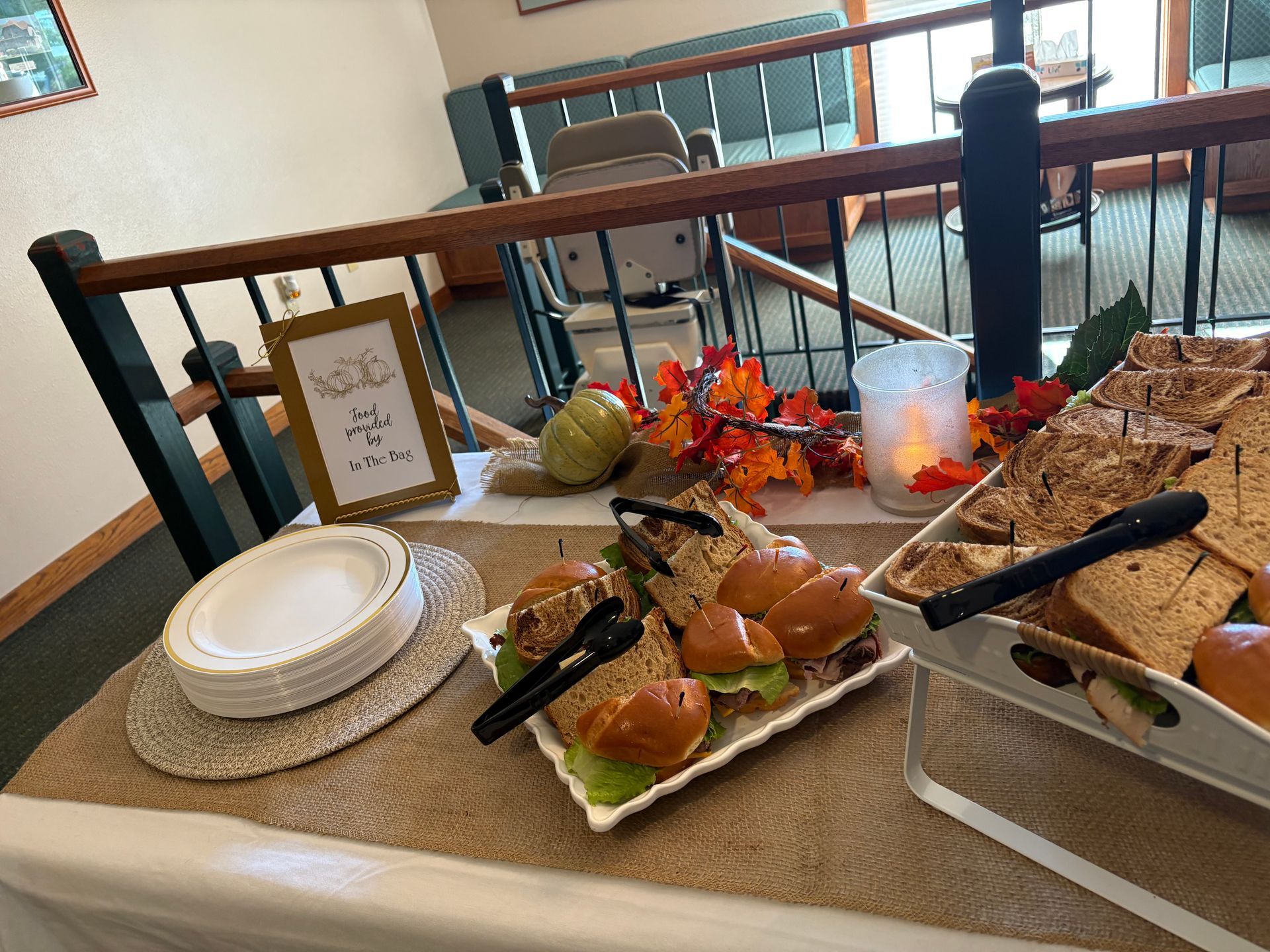 Buffet table with sandwiches, plates, and fall decorations.