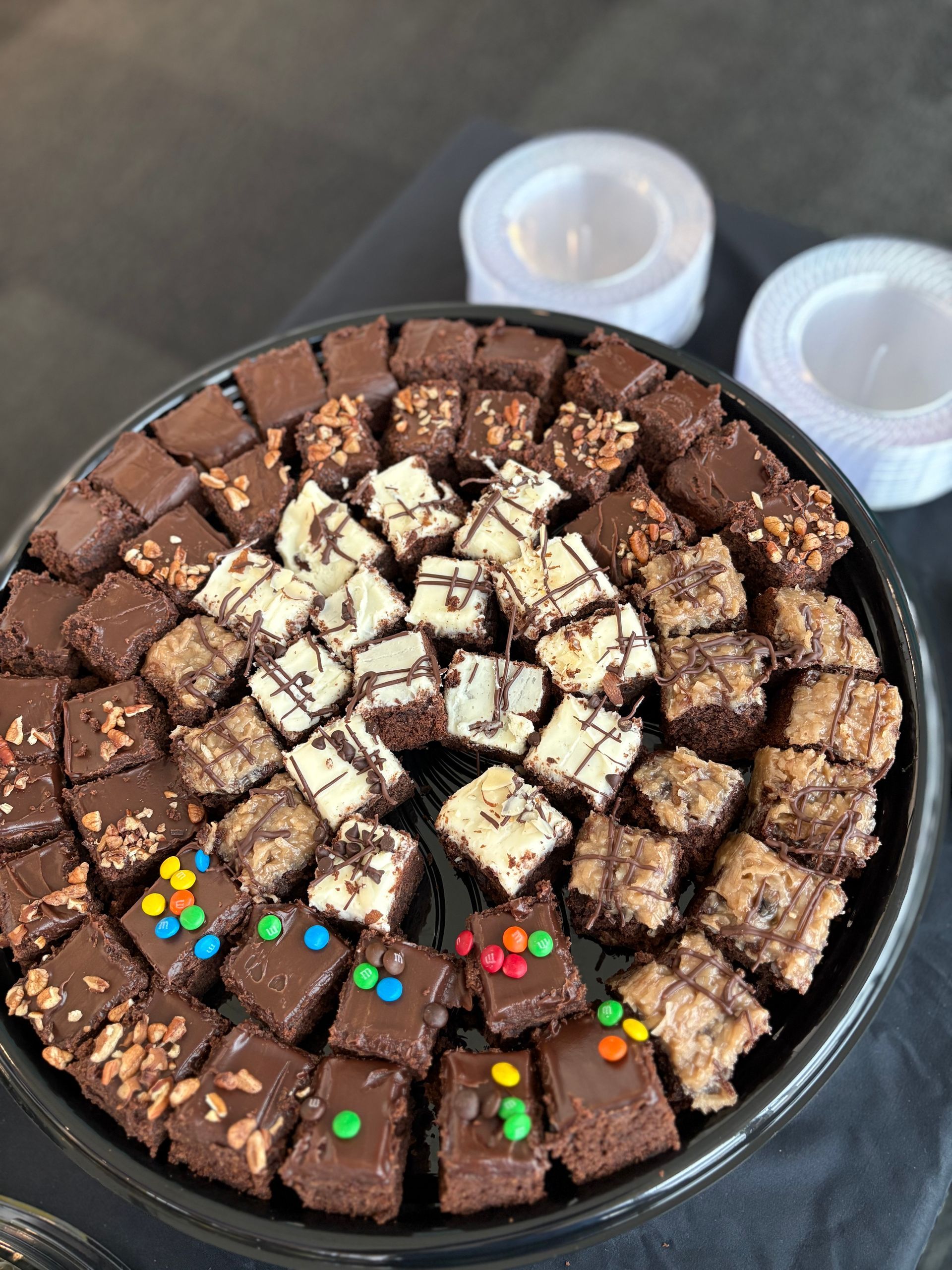 Brownie tray with various toppings and small white plates.