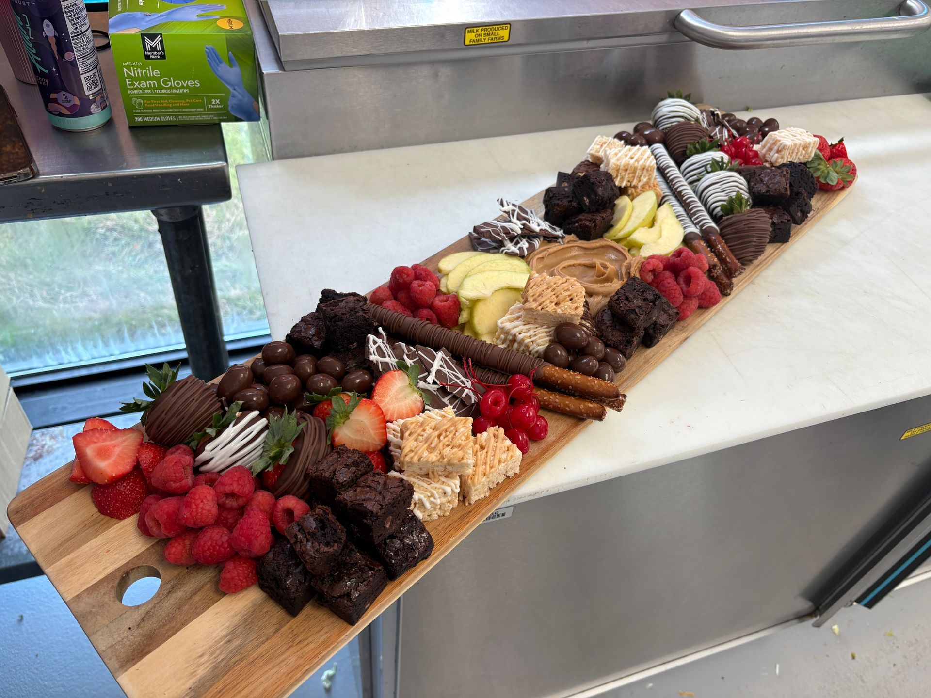Dessert charcuterie board: brownies, fruit, chocolates, rice crispy treats, on a wooden board.