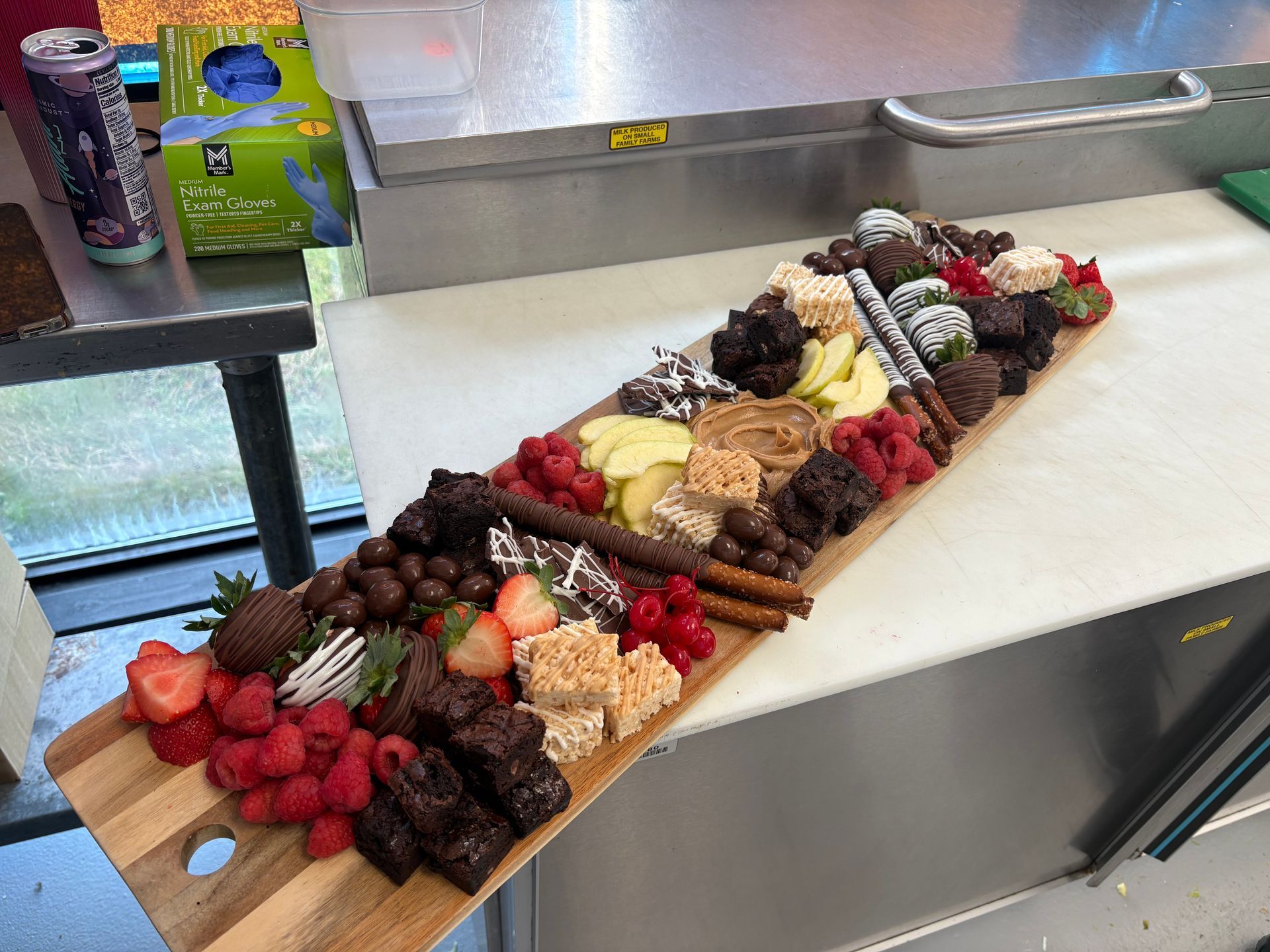Wooden charcuterie board with desserts: fruits, brownies, and candies.