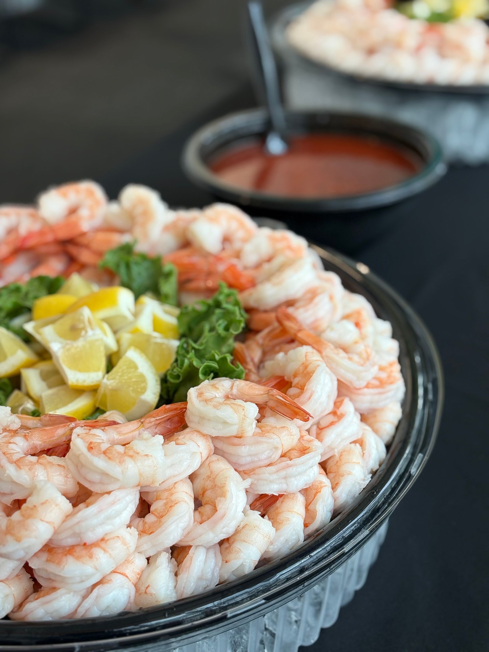 Shrimp platter with cocktail sauce and lemon wedges.