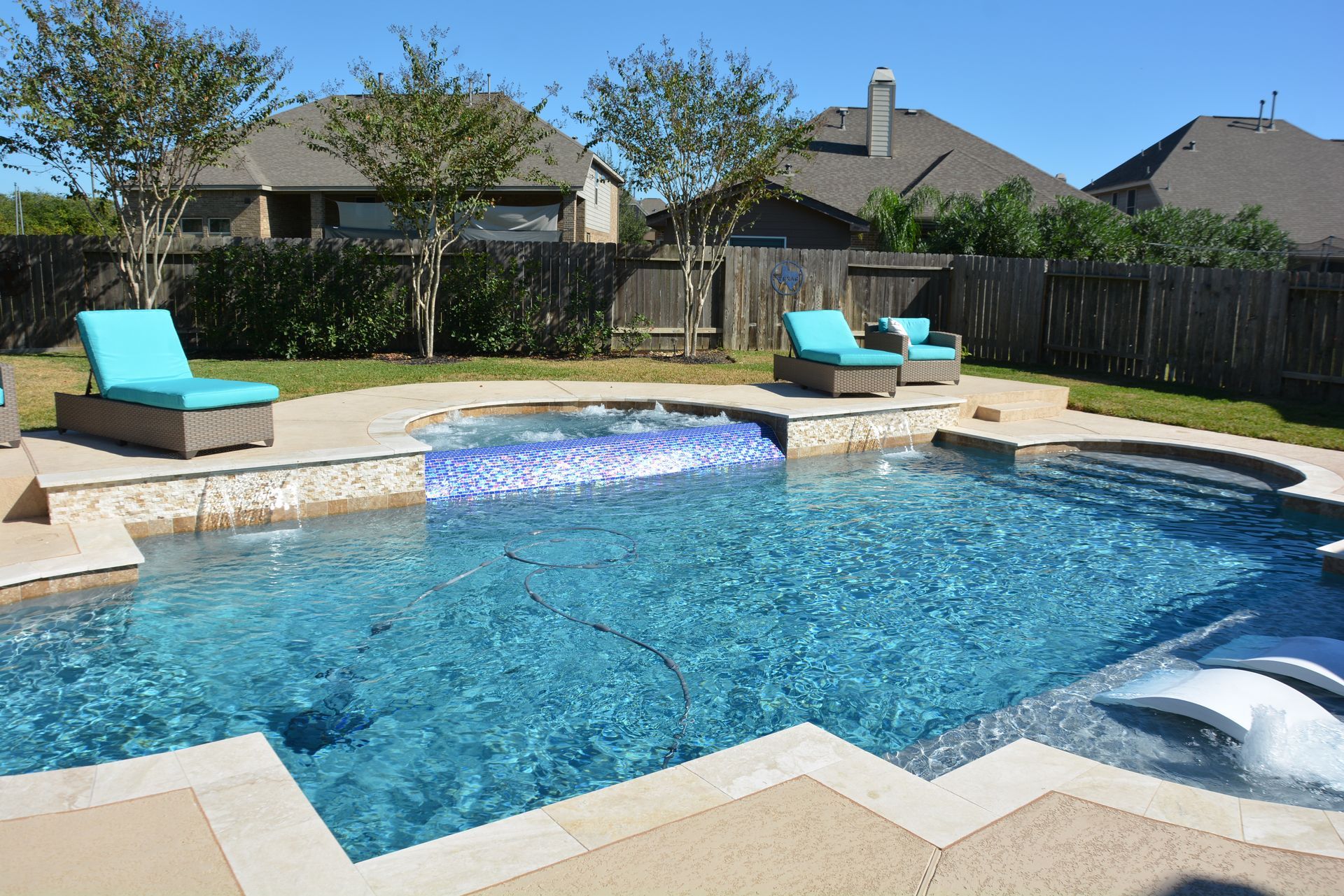 Backyard swimming pool with turquoise loungers and a raised spa under a clear sky