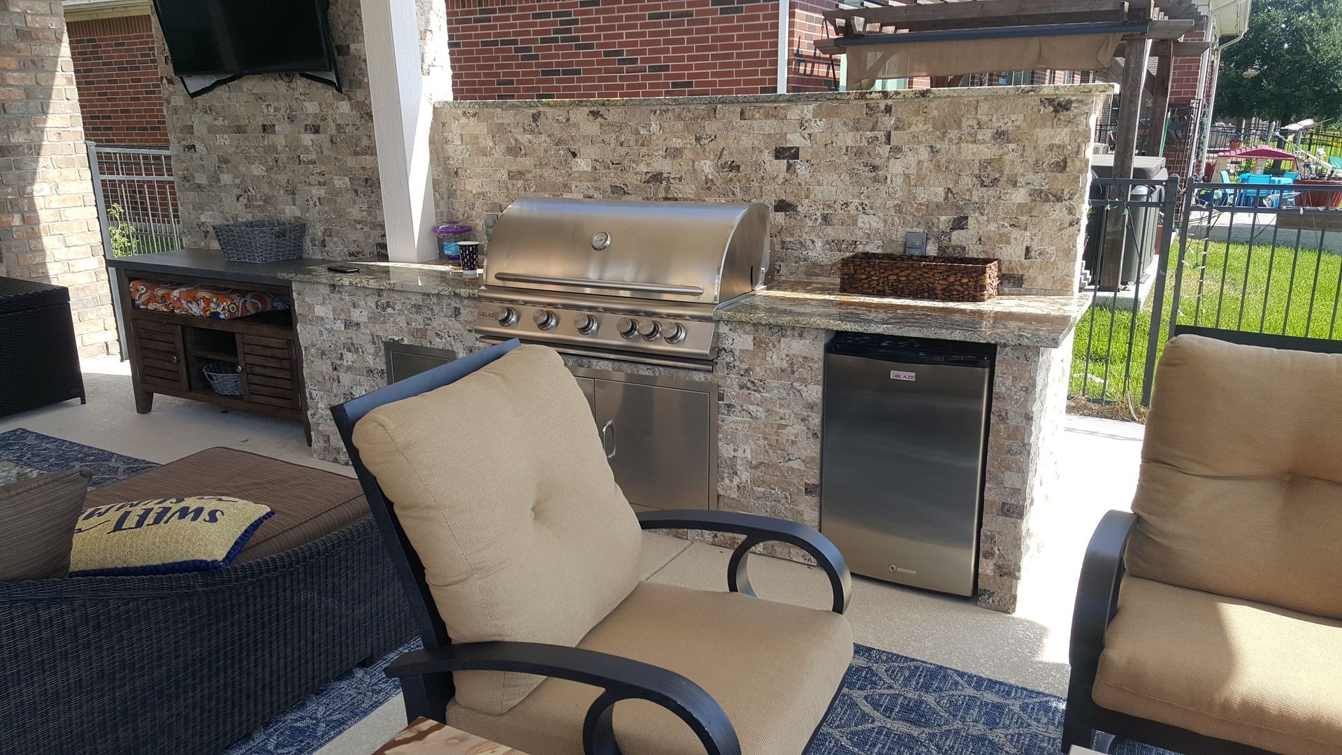 Outdoor patio with stone grill, metal storage cabinet, and cushioned chairs around a table