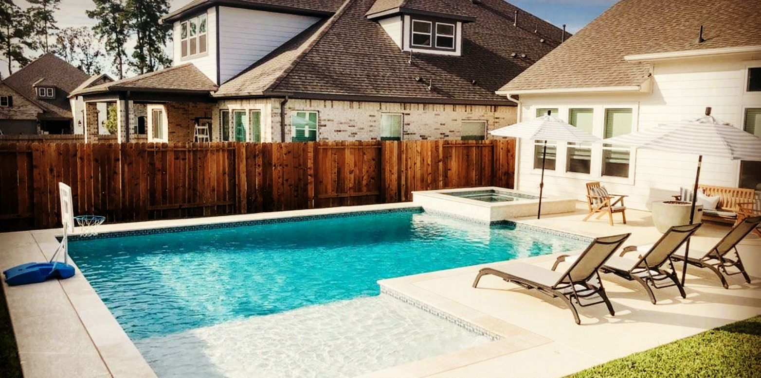 Backyard pool with white patio, lounge chairs, and wooden fence beside neighboring houses