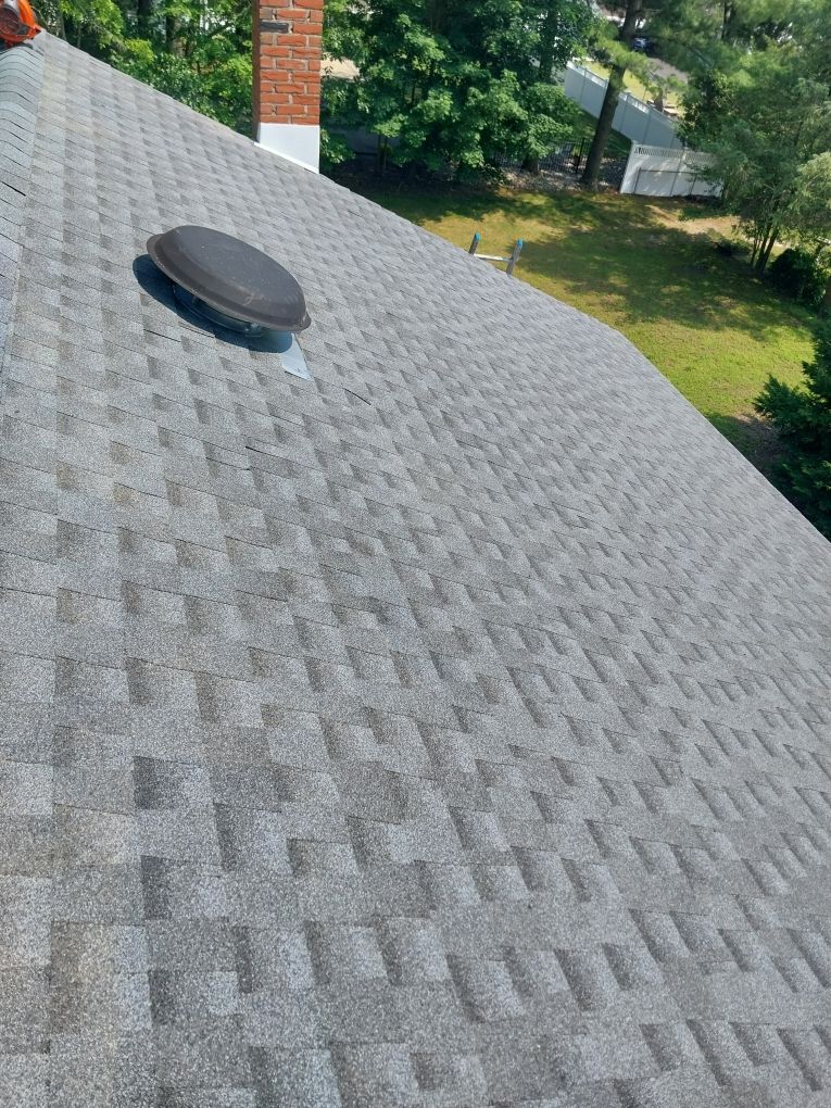 Gray shingled roof with vent, chimney, and green yard visible.