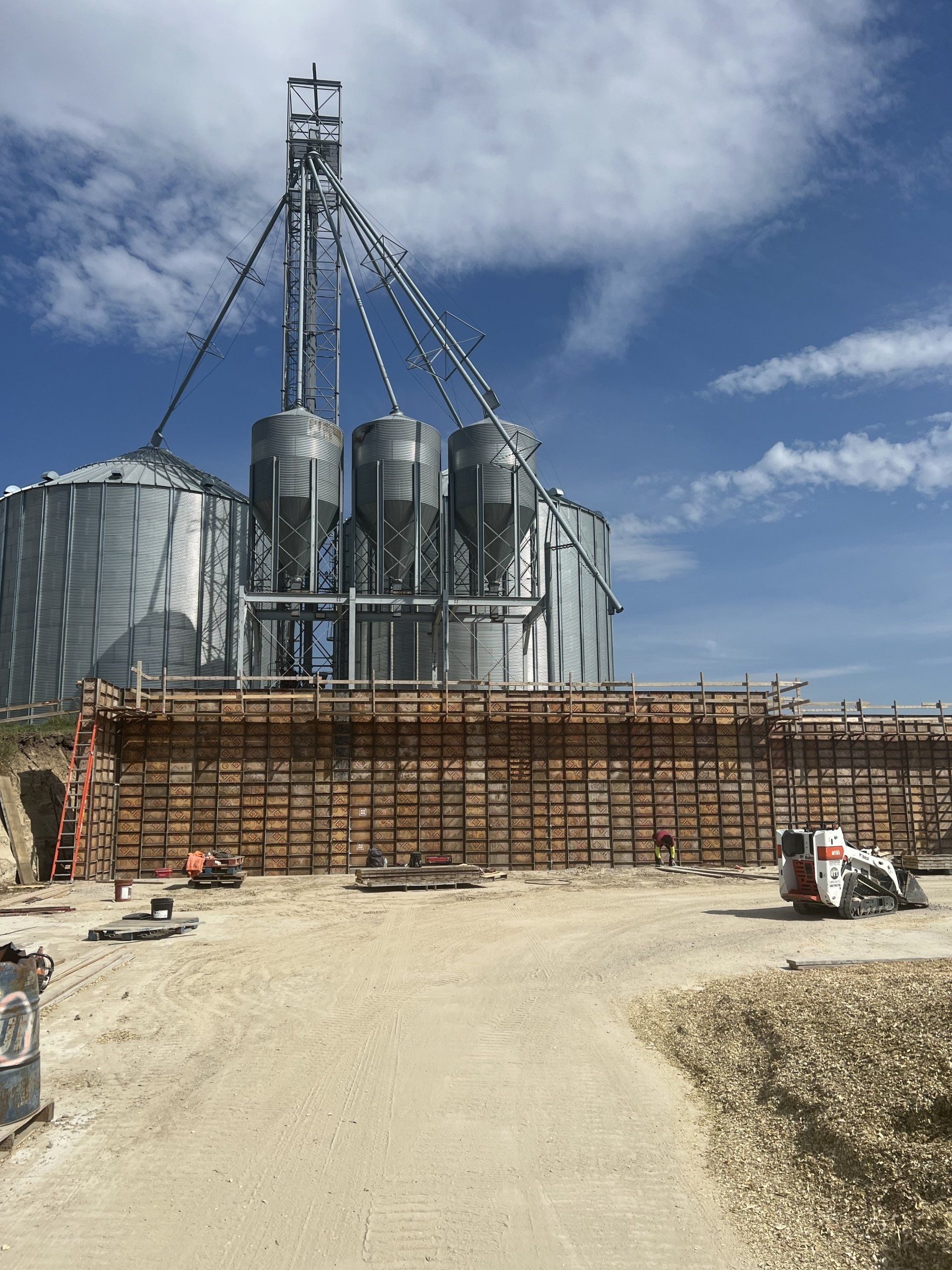 A large building under construction with silos in the background
