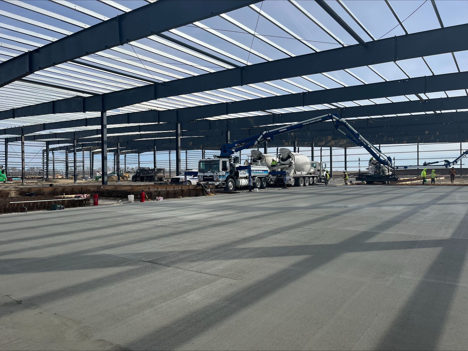 A concrete pump is being used to pour concrete into a large building under construction