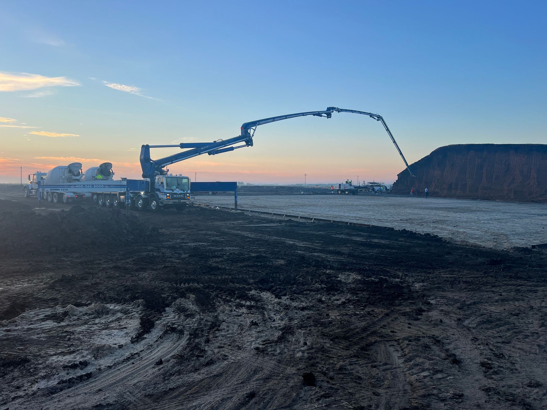 A concrete pump is pouring concrete into a large pile of dirt